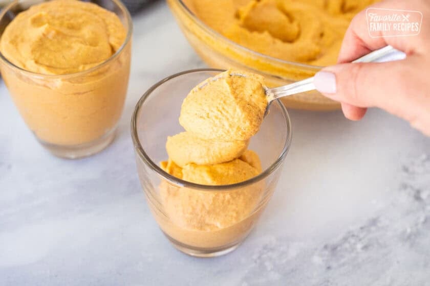 Spooning pumpkin mousse into glasses.