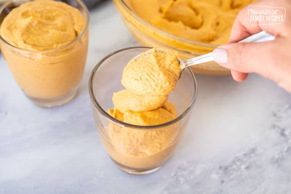 Spooning pumpkin mousse into glasses.