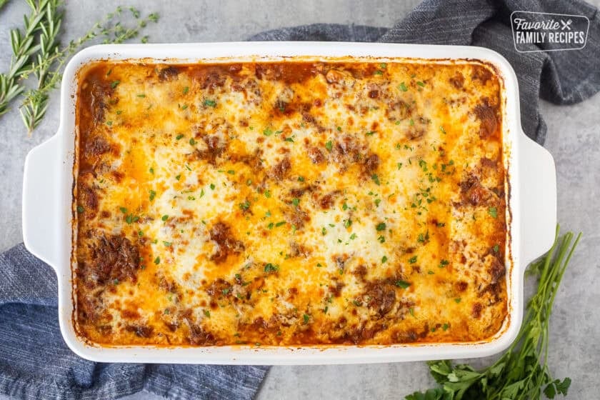 Baked short rib lasagna in a baking dish and garnished with fresh parsley.