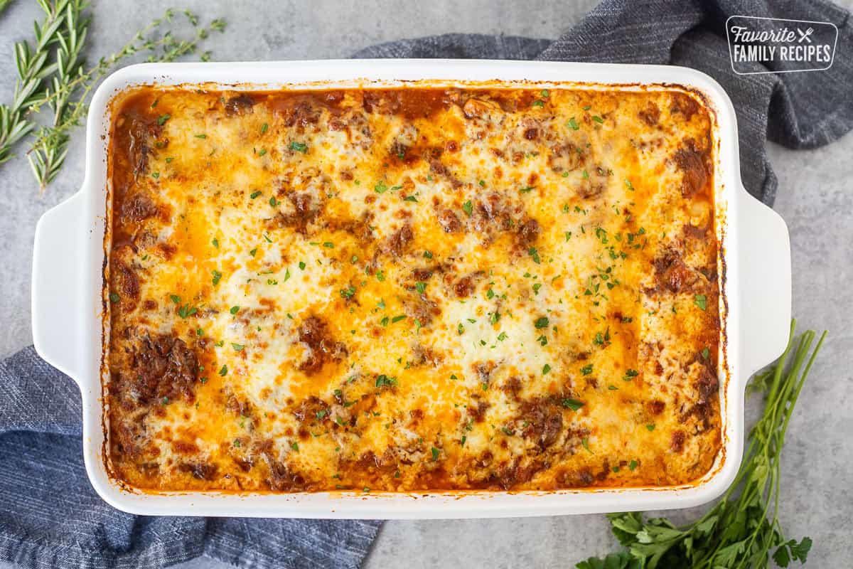 Baked short rib lasagna in a baking dish and garnished with fresh parsley.