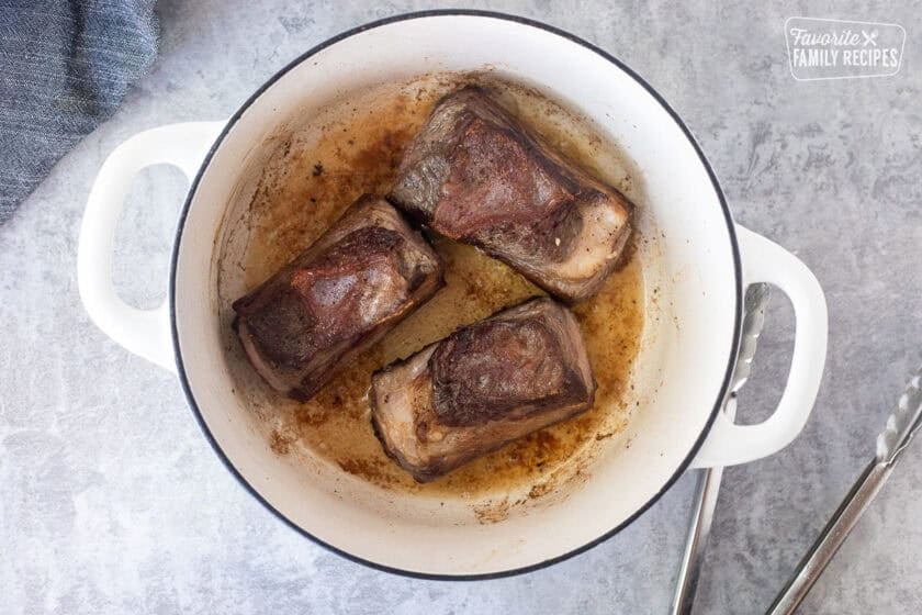 Browned sides of beef short ribs in a dutch over with olive oil.