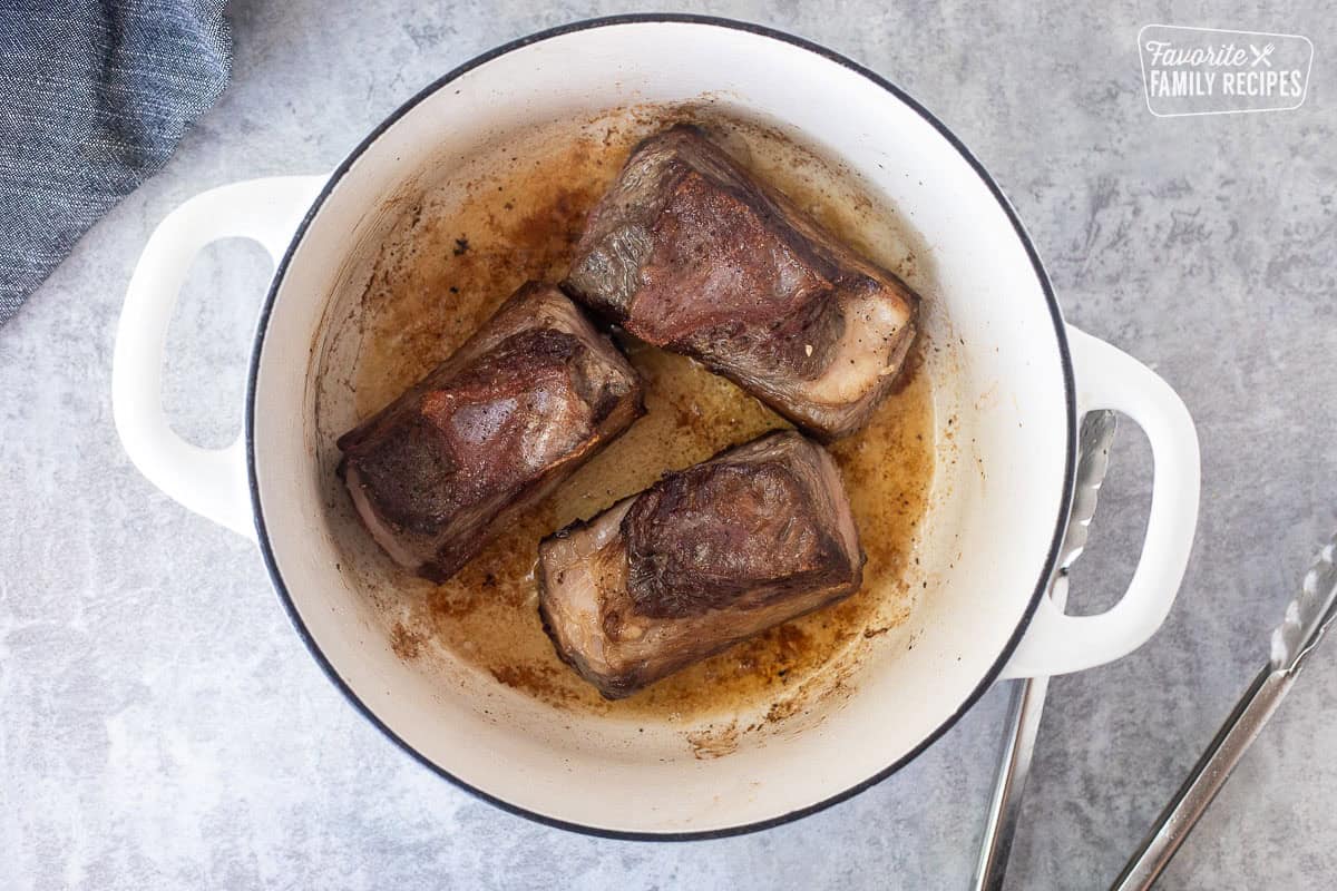 Browned sides of beef short ribs in a Dutch oven with olive oil.