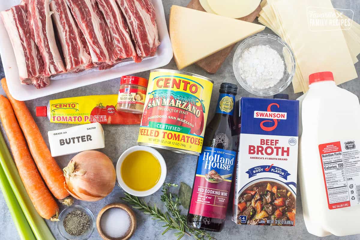 Ingredients to make short rib lasagna including whole milk, flour, lasagna noodles, cheeses, beef broth, canned tomatoes, red wine, rosemary, thyme, bay leaves, salt, olive oil, pepper, yellow onion, carrot, celery, tomato paste, short ribs and nutmeg.