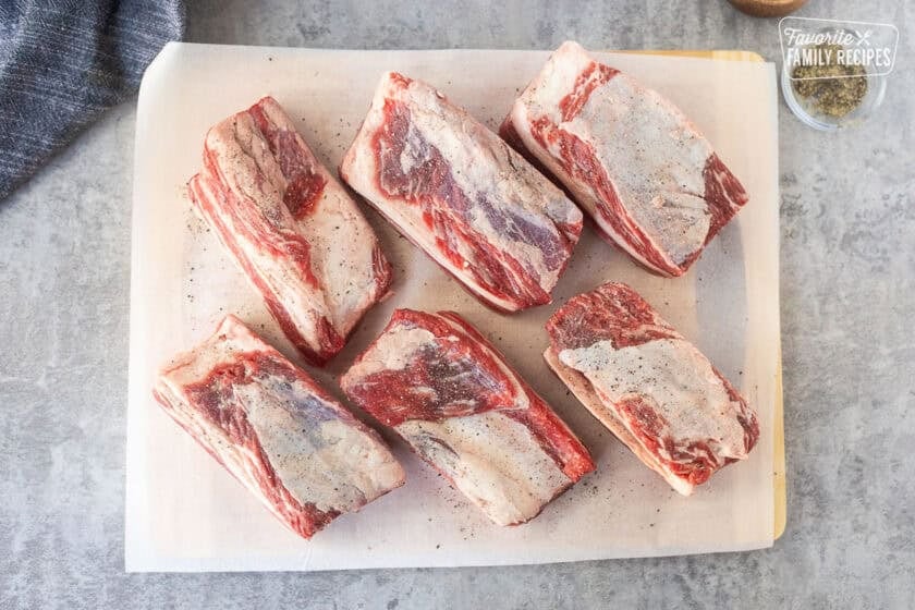Short ribs on parchment paper with salt and pepper.