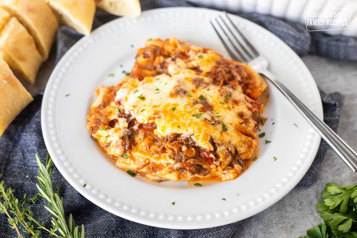 Slice of short rib lasagna on a plate with a fork.