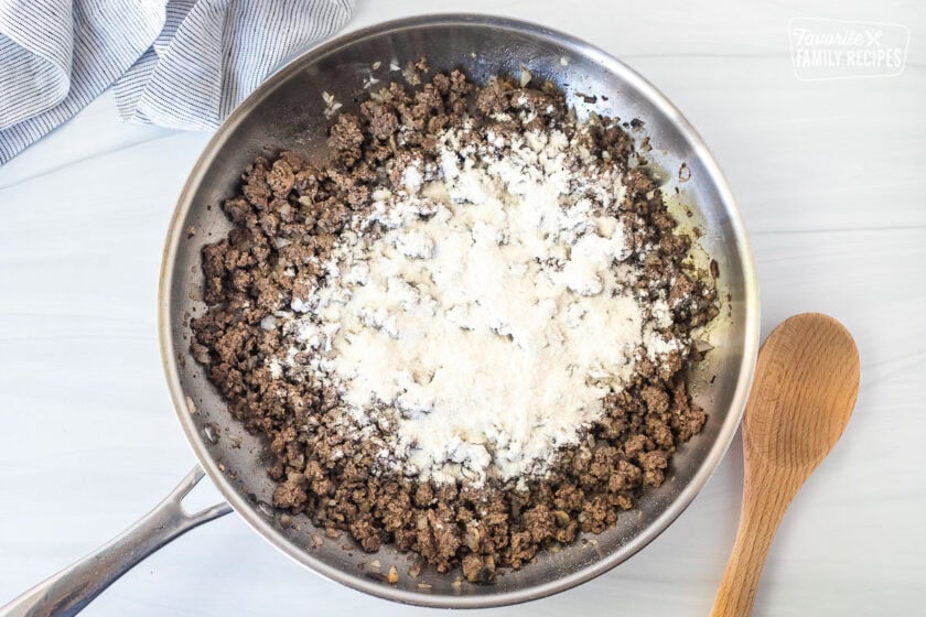Skillet with ground beef and flour on top.