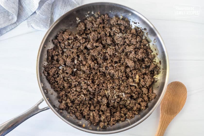 Skillet with brown ground beef, mushrooms and onions.