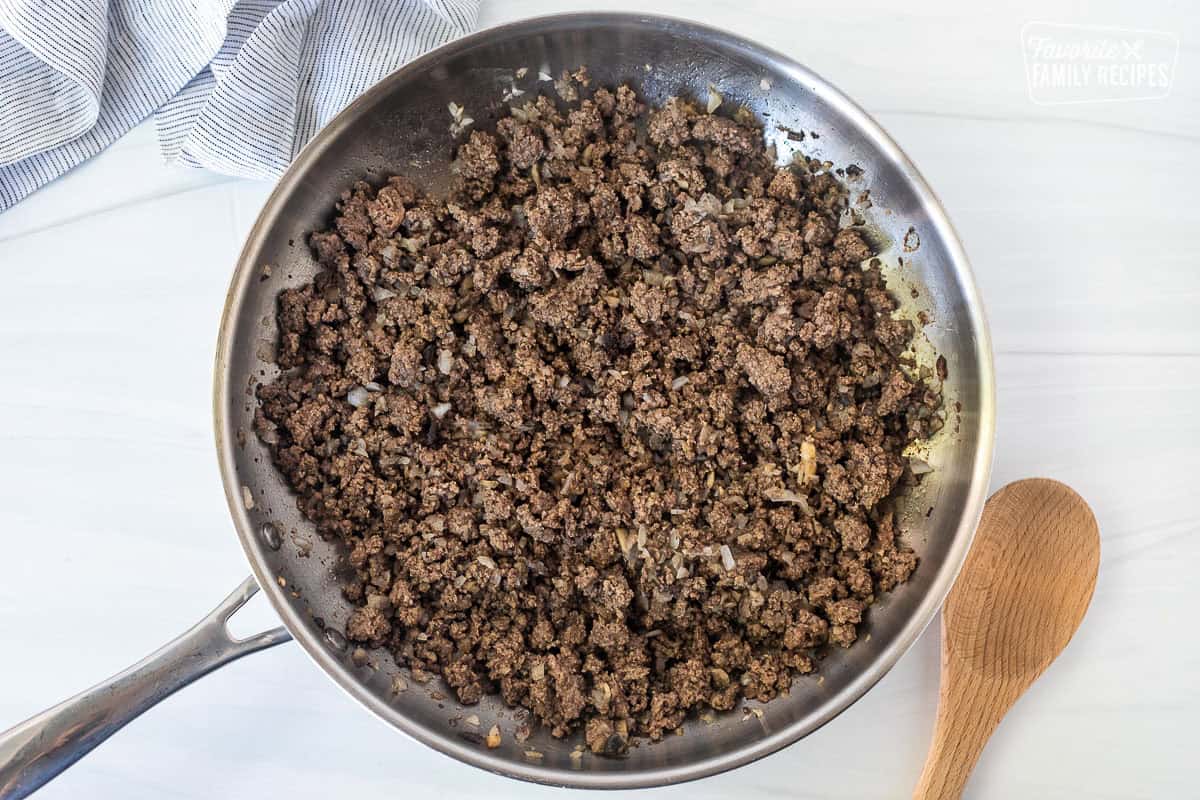 Skillet with brown ground beef, mushrooms and onions.