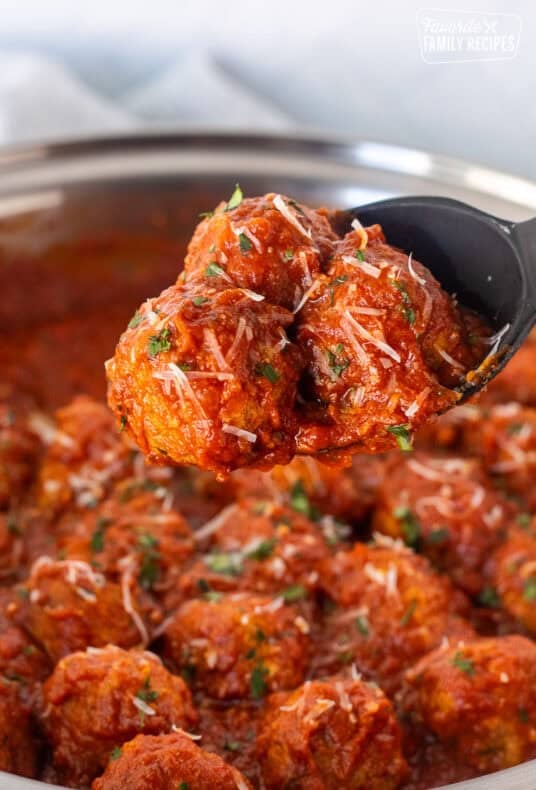 Turkey meatballs in a skillet with sauce being lifted with a serving spoon