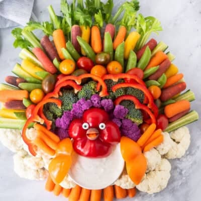 Large round tray with arranged vegetables shaped like a turkey and a small bowl of Ranch dip.