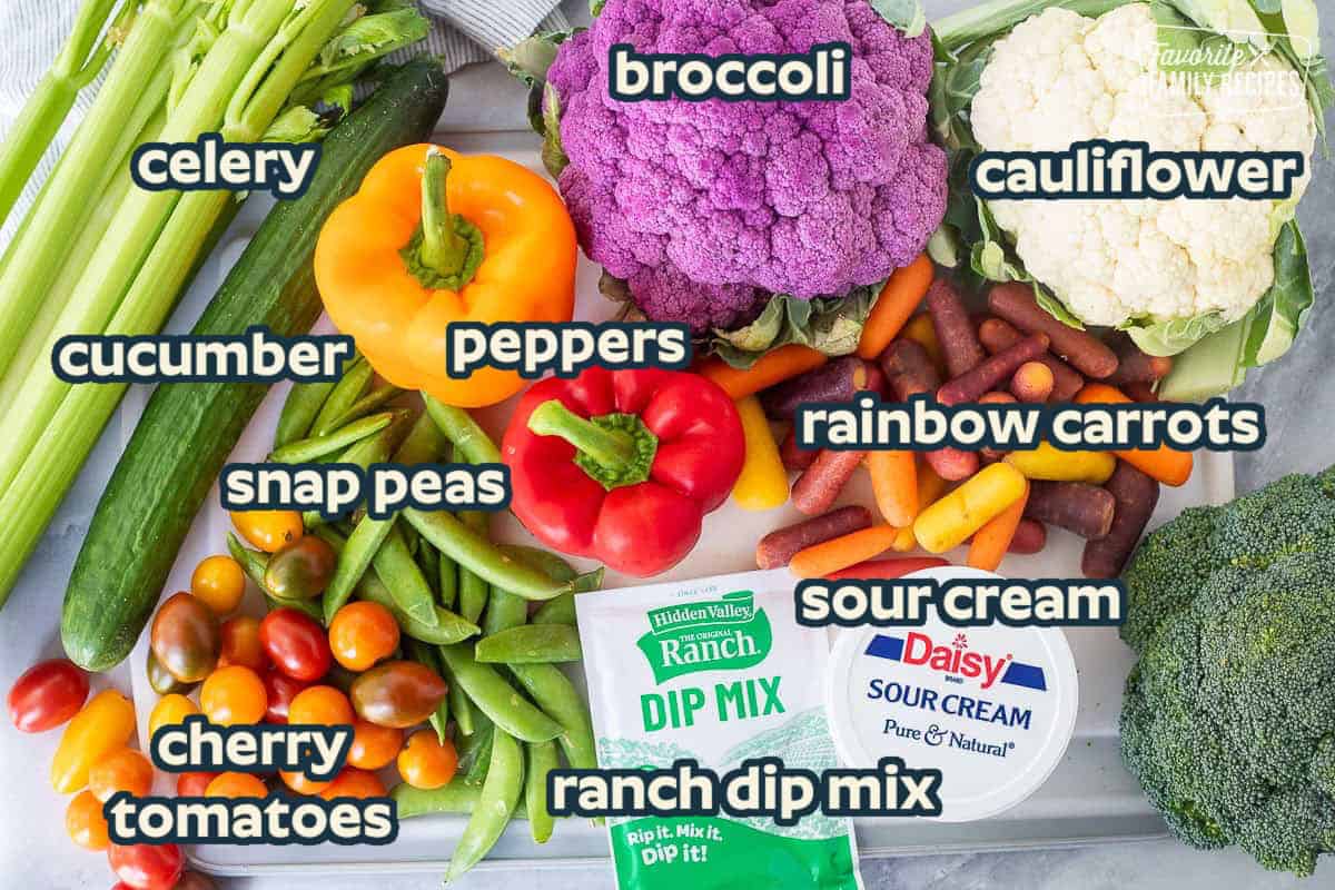 Ingredients to make turkey veggie tray including broccoli, cauliflower, purple cauliflower, multi color baby carrots, sour cream, Ranch dip mix packet, sugar snap peas, bell peppers, tomatoes, cucumber, and celery.
