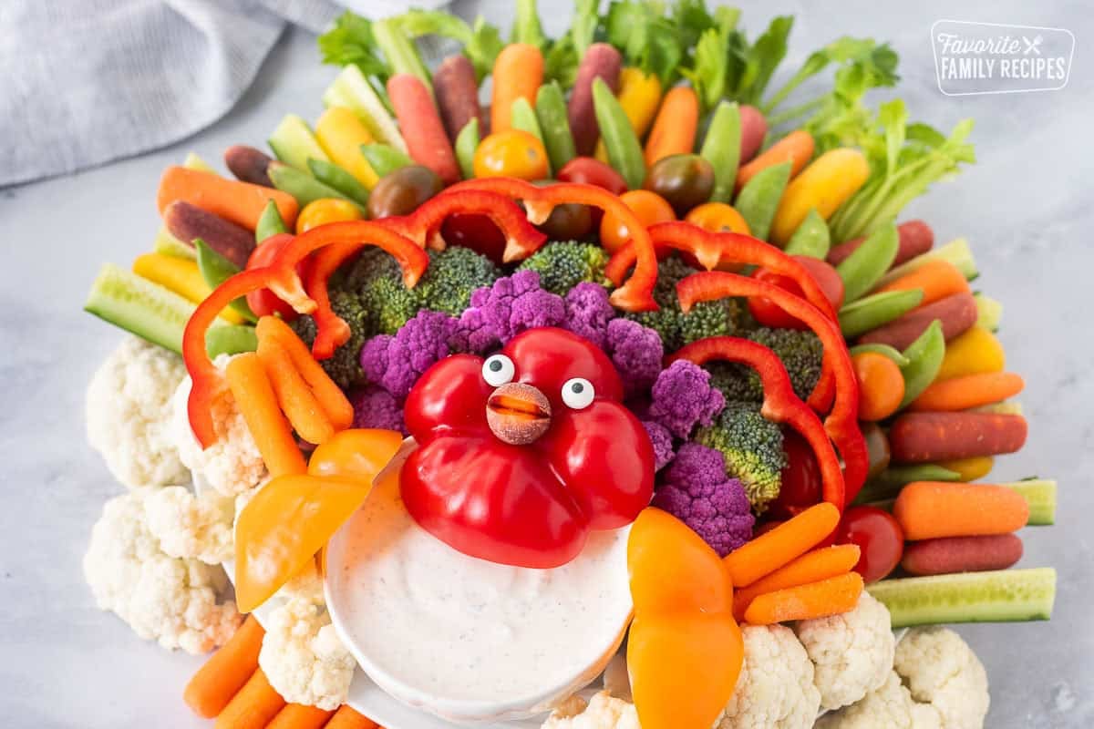 Large round tray with arranged vegetables shaped like a turkey and a small bowl of Ranch dip.