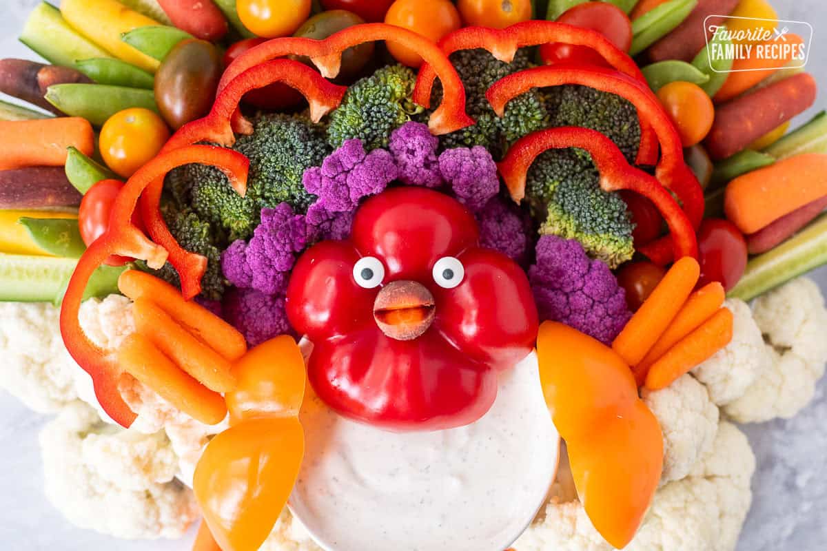 Colorful vegetables arranged like a turkey face with candy eyes and carrot beak.