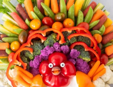 Large round tray with arranged vegetables shaped like a turkey and a small bowl of Ranch dip.