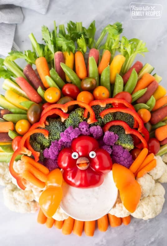 Large round tray with arranged vegetables shaped like a turkey and a small bowl of Ranch dip.