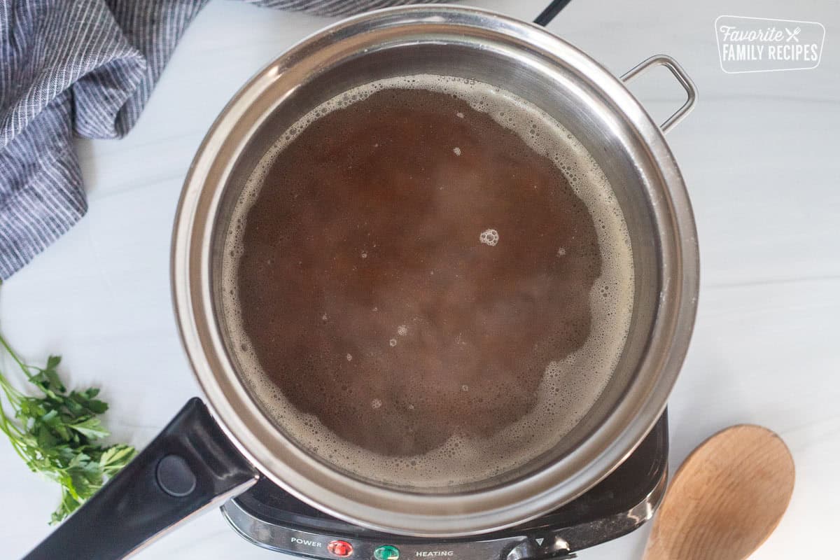 Sauce pan with wild rice, chicken stock and butter simmering on an electric skillet.