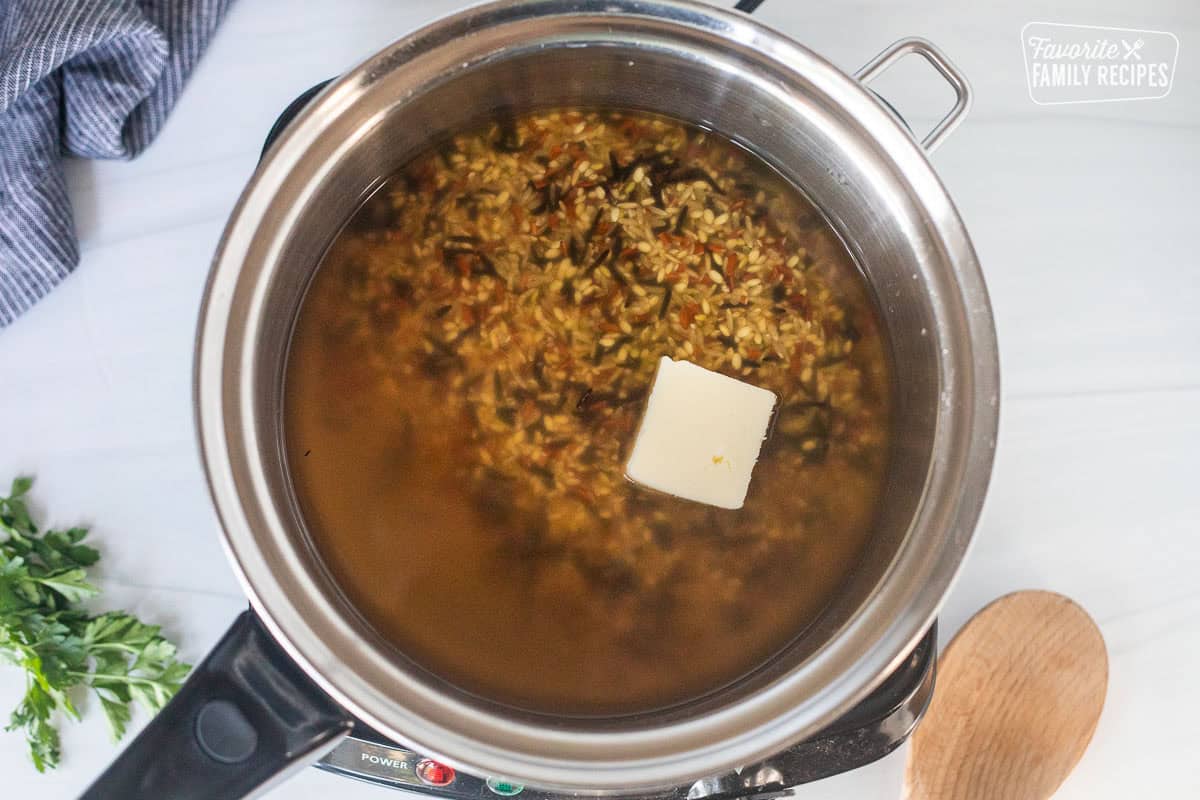 Saucepan with wild rice, chicken stock and butter.