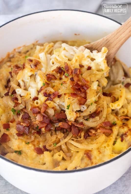 Scooping up Alplermagronen from dutch oven with a wooden spoon.