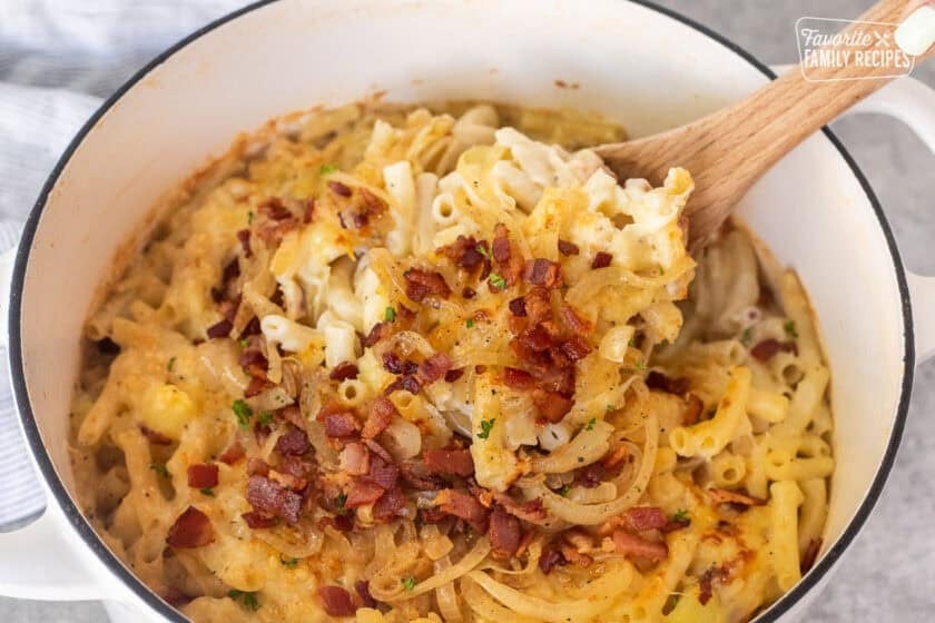 Scooping up Alplermagronen from dutch oven with a wooden spoon.