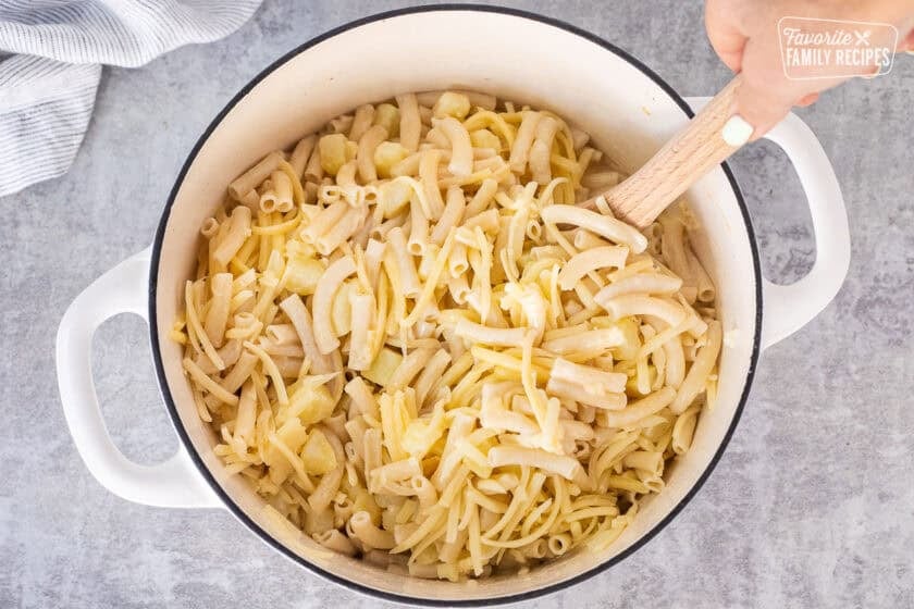 Stirring in the shredded cheese to Alplermagronen in dutch oven.