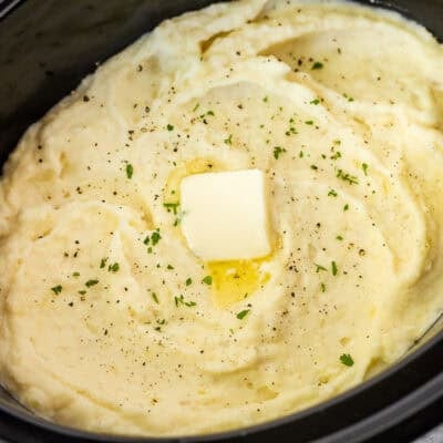 Creamy Crockpot mashed potatoes topped with butter, black pepper, and fresh parsley.
