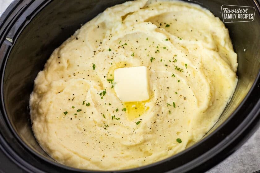 Creamy Crockpot mashed potatoes topped with butter, black pepper, and fresh parsley.