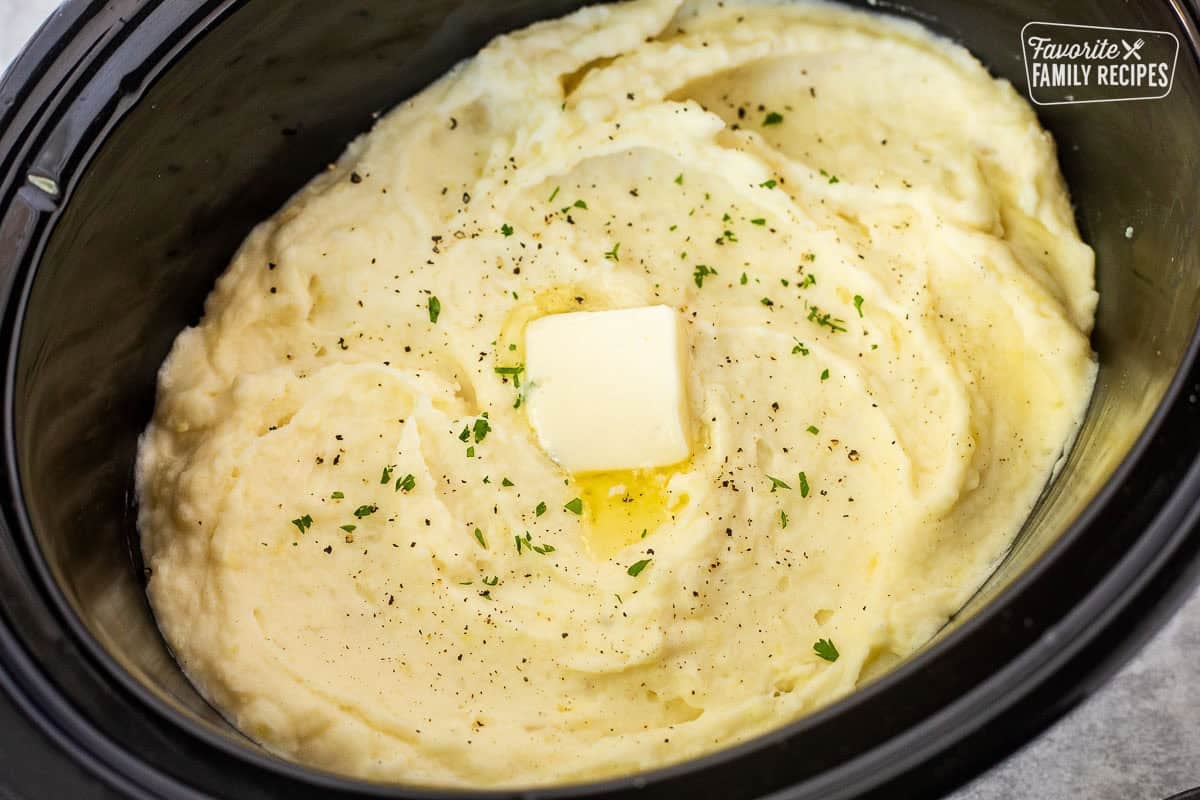Creamy Crockpot mashed potatoes topped with butter, black pepper, and fresh parsley.