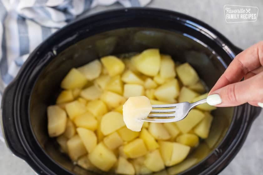 Fork piercing a cooked potato to check for tenderness.
