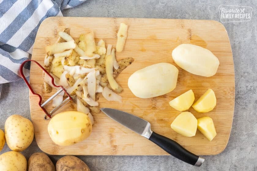 Cutting board with peeled and cut potatoes.