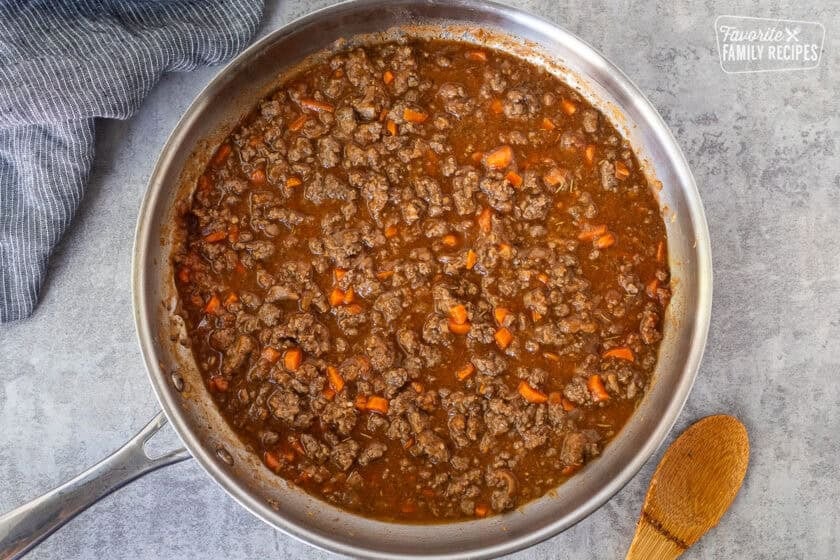 Tomato sauce, ground beef, carrots and onion in a skillet.