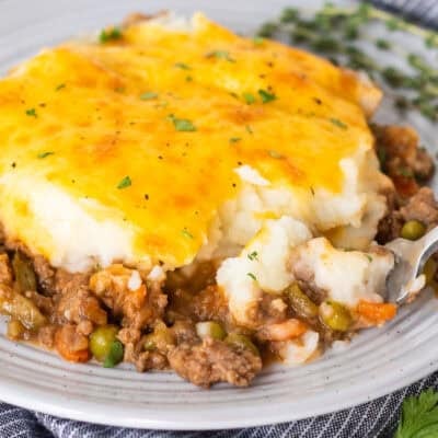 Plate of shepherds pie with a fork removing a corner bite.