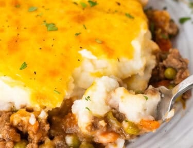 Plate of shepherds pie with a fork removing a corner bite.