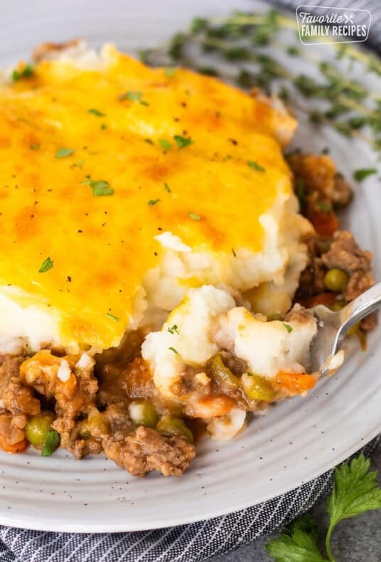 Plate of shepherds pie with a fork removing a corner bite.