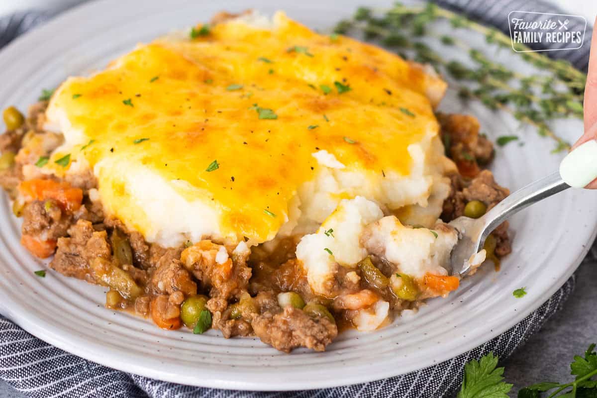 Plate of shepherds pie with a fork removing a corner bite.