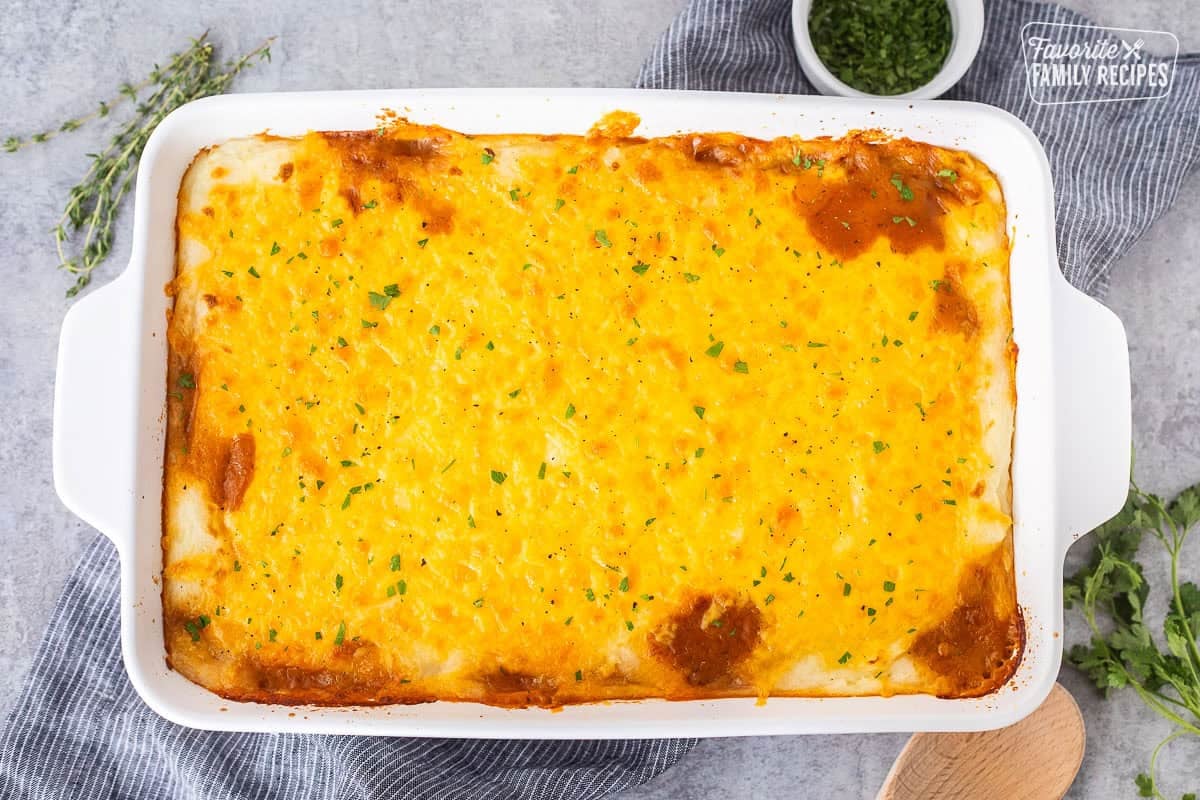 Baked shepherds pie in a casserole dish garnished with fresh parsley.