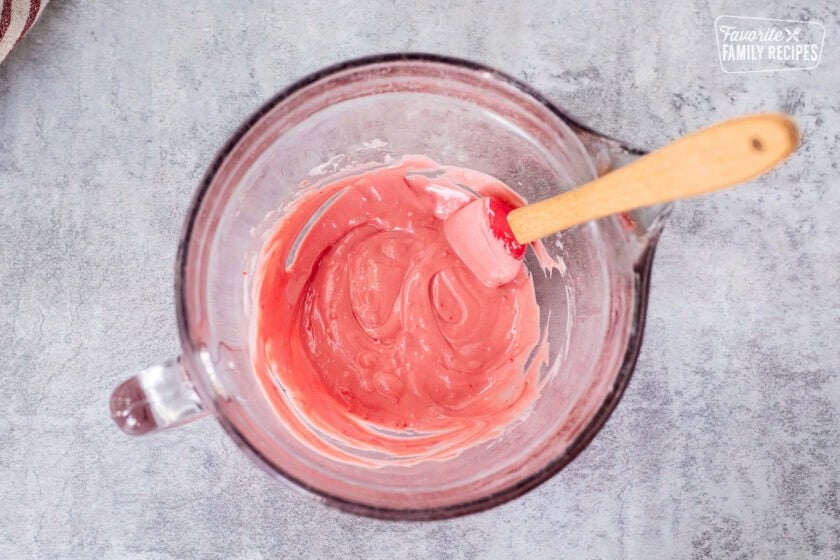 Stirring melted peppermint chips white chocolate mixture in a bowl.