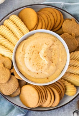 Plate with a center bowl of pumpkin dip surrounded by ginger pumpkin cookies, vanilla wafers and ginger snaps.